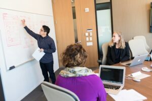 Man writing on whiteboard at a meeting discussing the upcoming business transitions